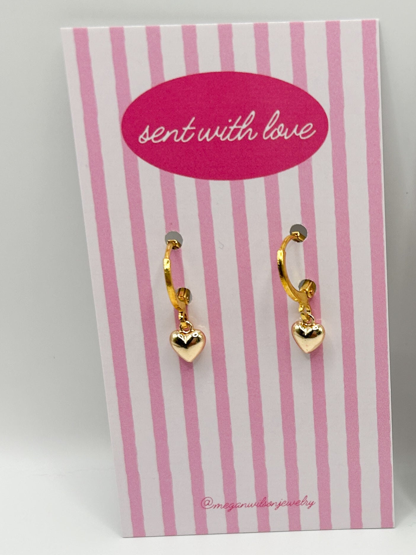 Two pairs of gold bow-shaped earrings on pink and white striped cards with 'sent with love' text.
